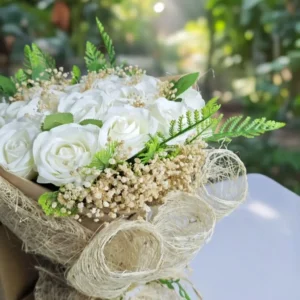 Kraft kağıt ve hasır jüt dokulu ambalaj içerisinde cipsolarla zenginleştirilmiş el emeği beyaz gül buketi.